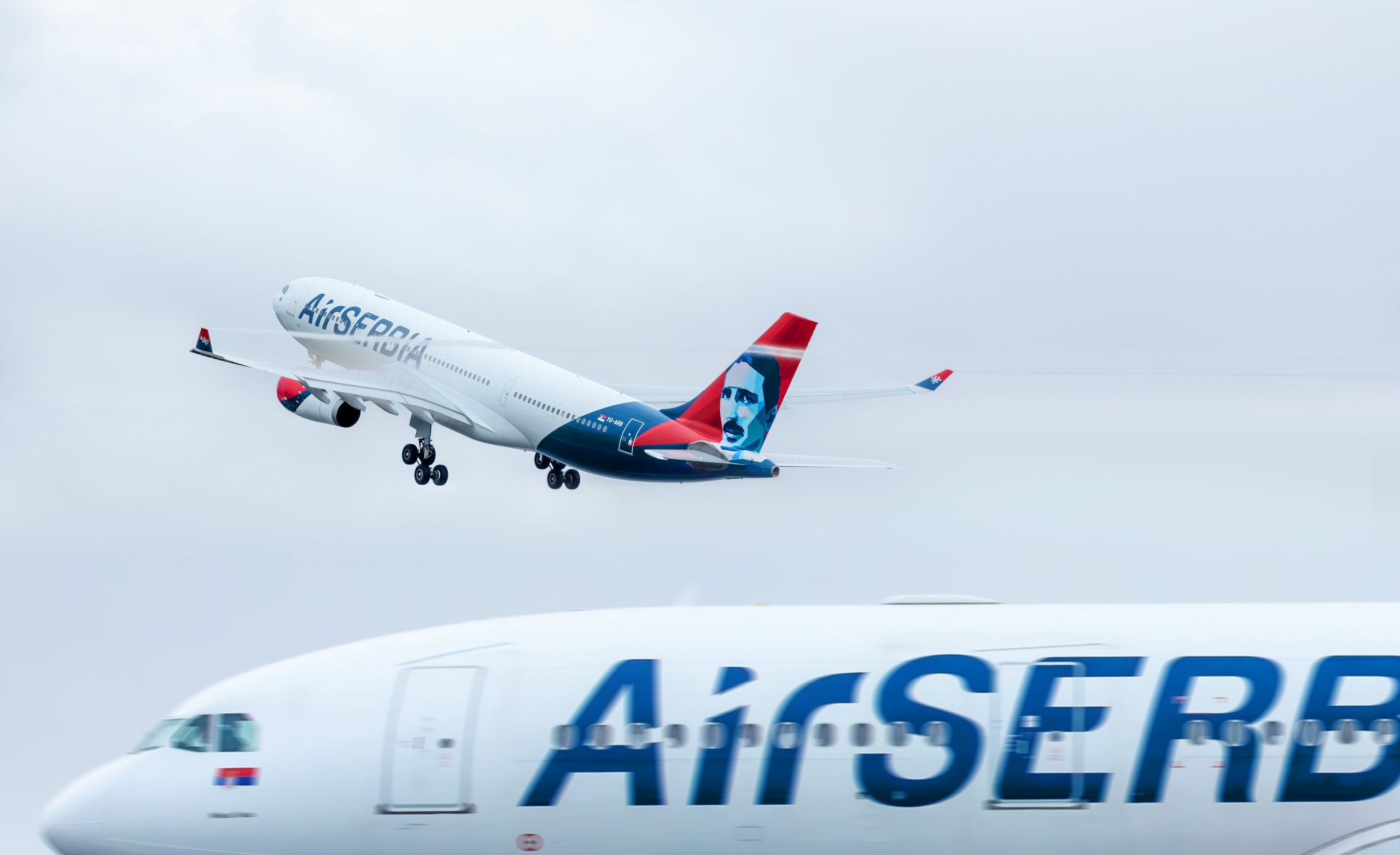 Photograph of two Air Serbia aircraft - one in the air and one in the foreground
